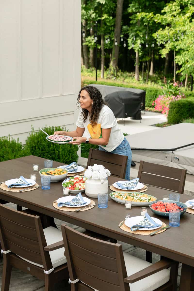 Yumna in outdoor patio with dining set and fruit salad dishes