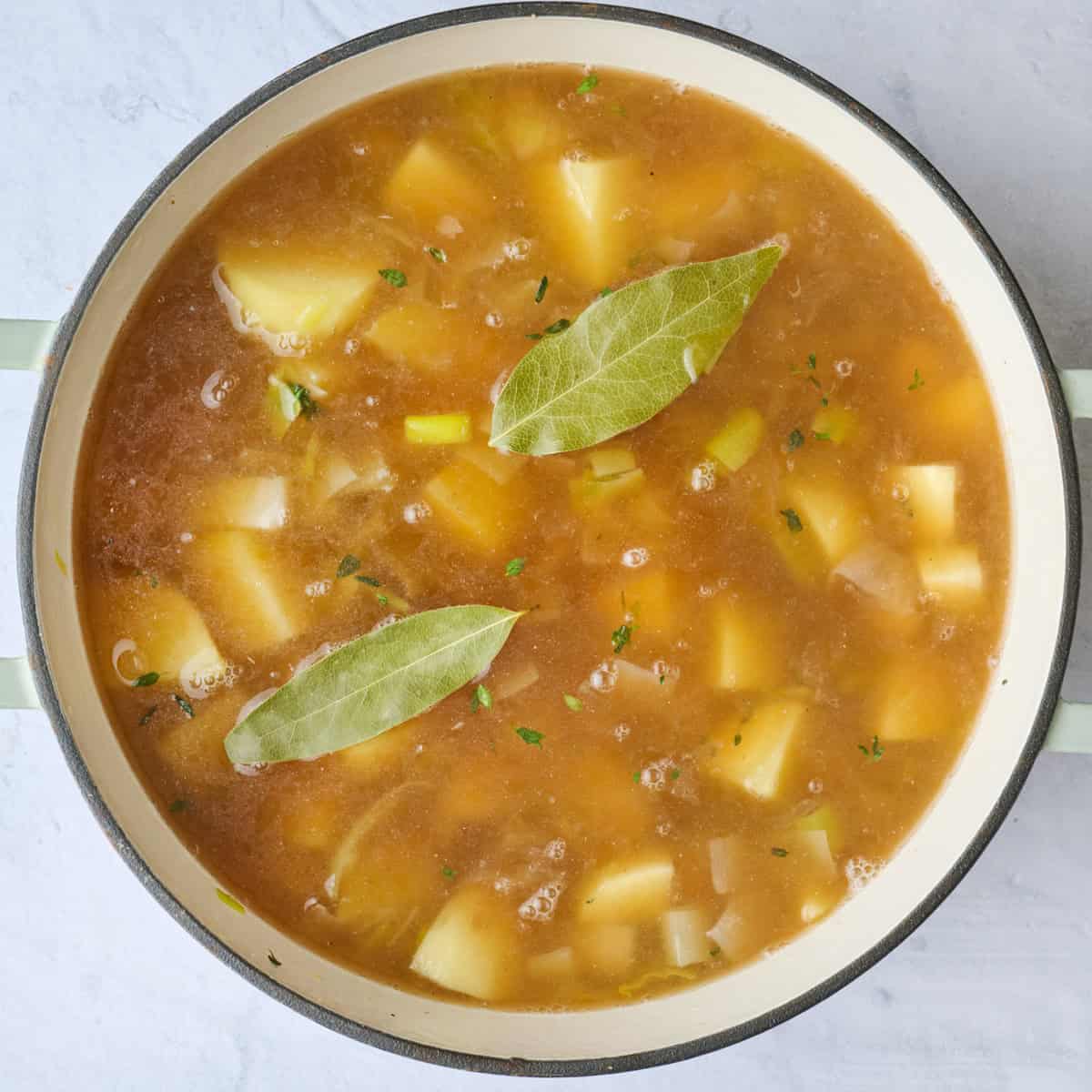 After broth and bay leaves are added to pot with chopped potatoes and leeks before boiling