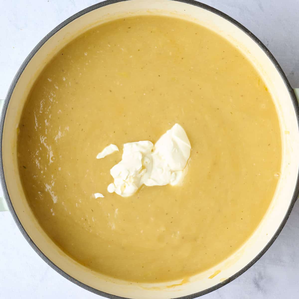 Creamy soup with sour cream added to pot before stirring.