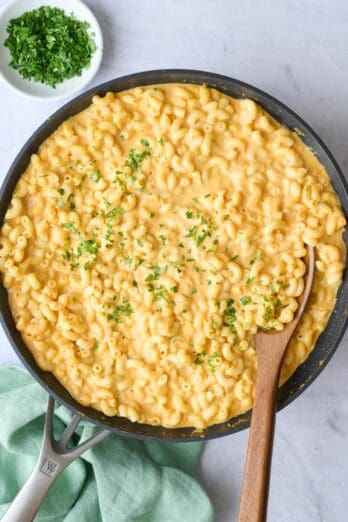 Pumpkin macaroni and cheese in skillet garnished with chopped parsley.