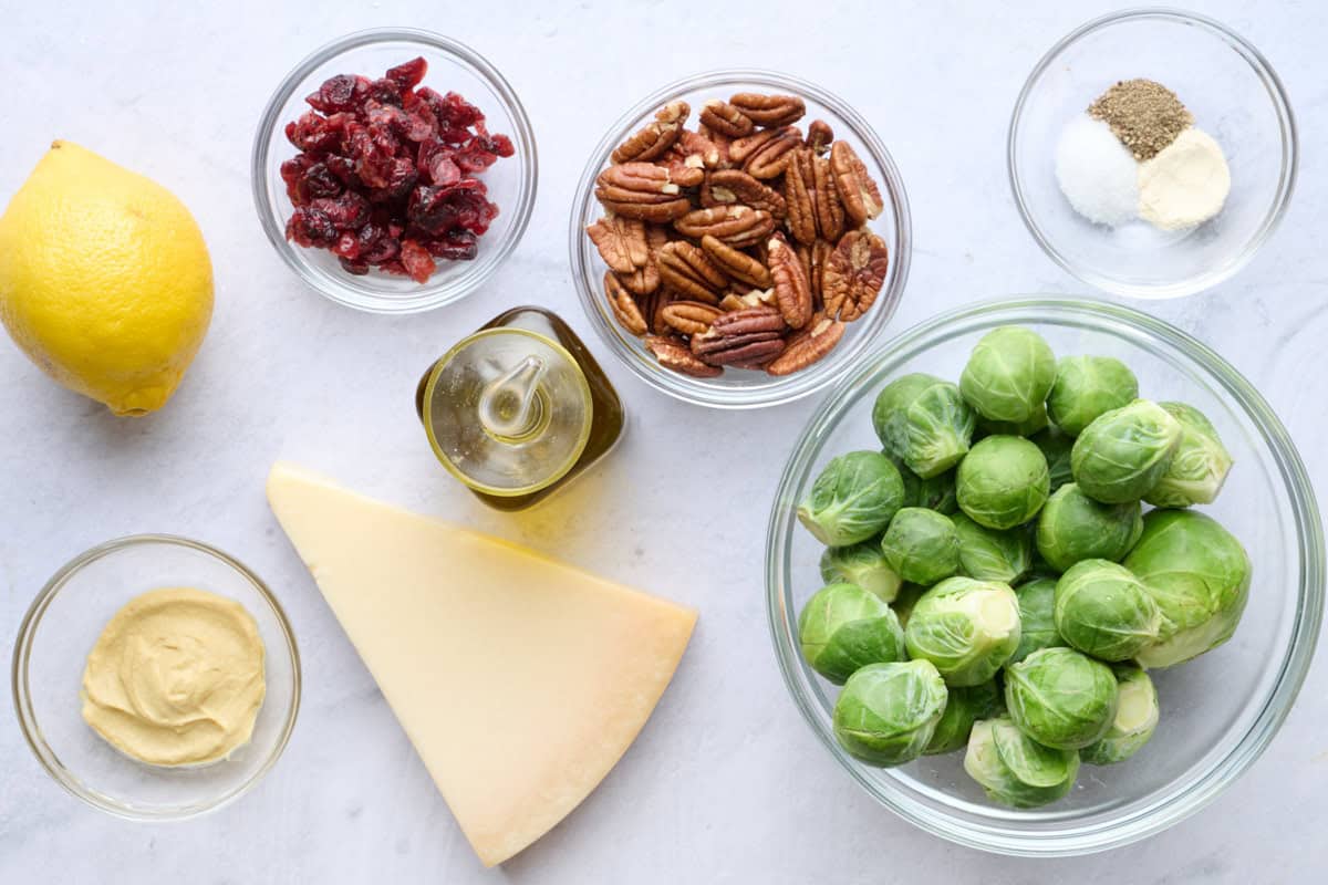 Ingredients for recipe: lemon, Dijon mustard, dried cranberries, oil, parmesan block, pecans, spices, and brussel sprouts.