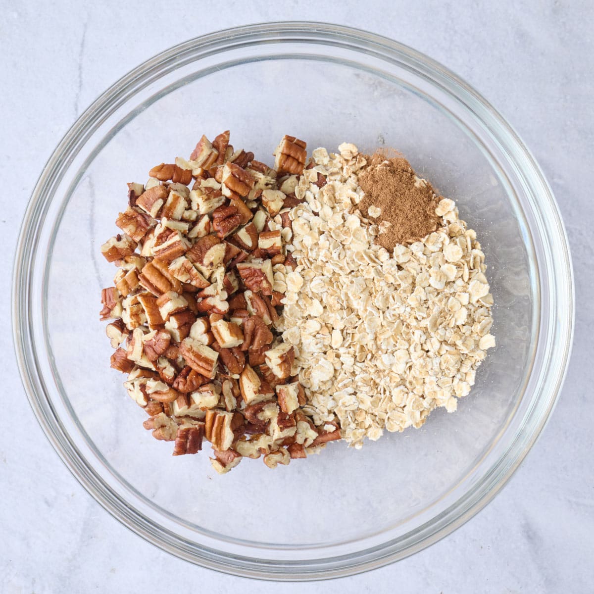 Pecans, oats and cinnamon in a bowl before mixing.