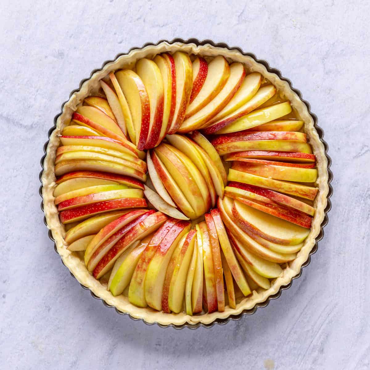 Sugar coated apple slices in the prepared puff pastry pie tart before baking.