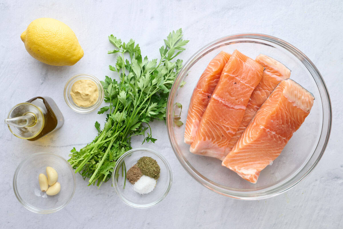 Ingredients for recipe: lemon, oil, garlic, Dijon mustard, fresh parsley, seasonings, and skin on salmon fillets.