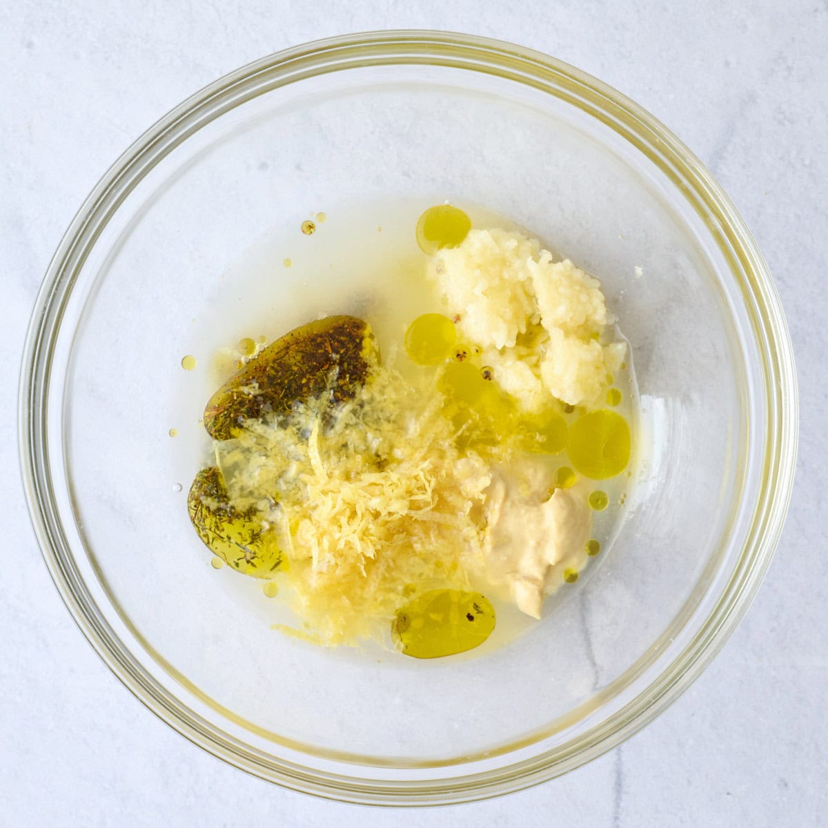 Olive oil, lemon juice, lemon zest, garlic, Dijon mustard, thyme, salt, and black pepper in a shallow before mixing for salmon recipe.