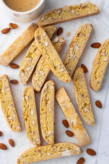 Almond biscotti recipe on parchment paper with a cup of coffee nearby for dipping.