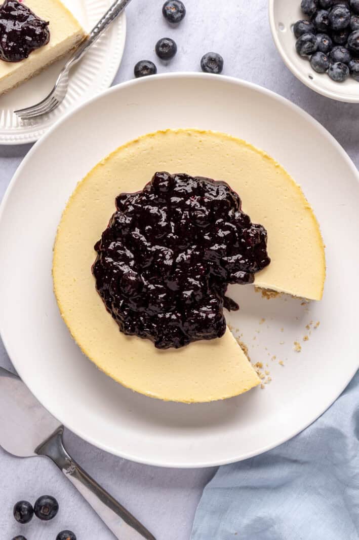 High protein cottage cheese cheesecake on a large platter served with a blueberry compote on top.