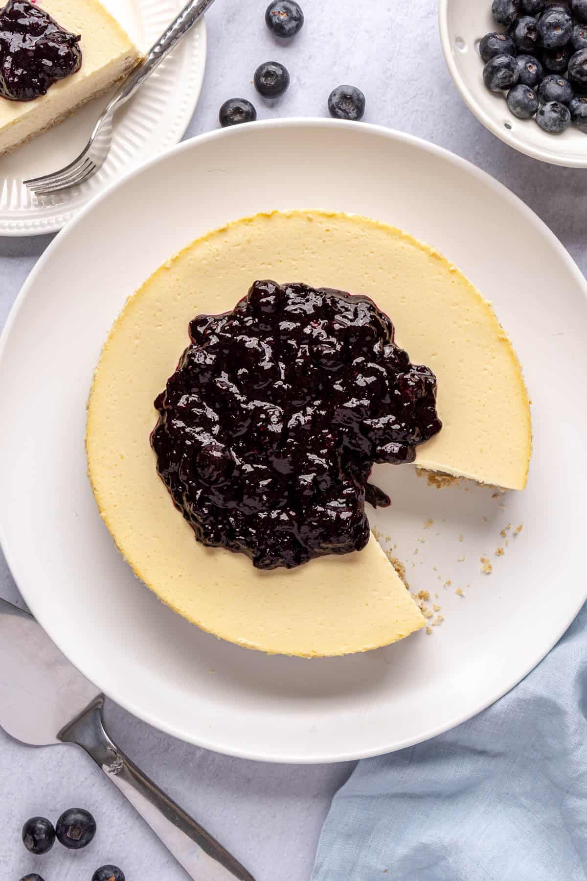 High protein cottage cheese cheesecake on a large platter served with a blueberry compote on top.