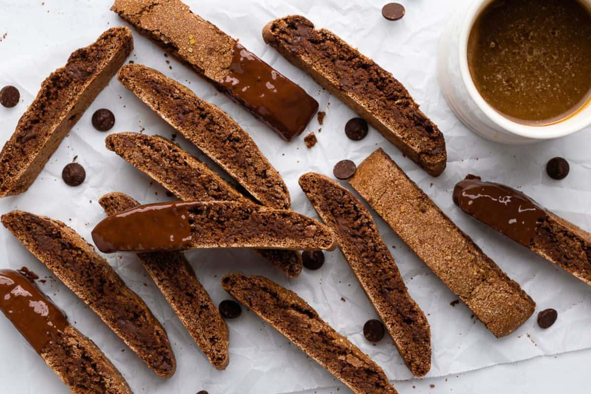 Dark chocolate chip biscotti recipe on parchment paper with a few dipped in chocolate.
