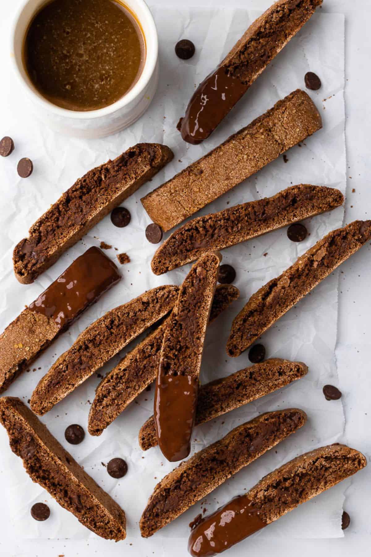 Dark chocolate chip biscotti recipe on parchment paper with a few dipped in chocolate.
