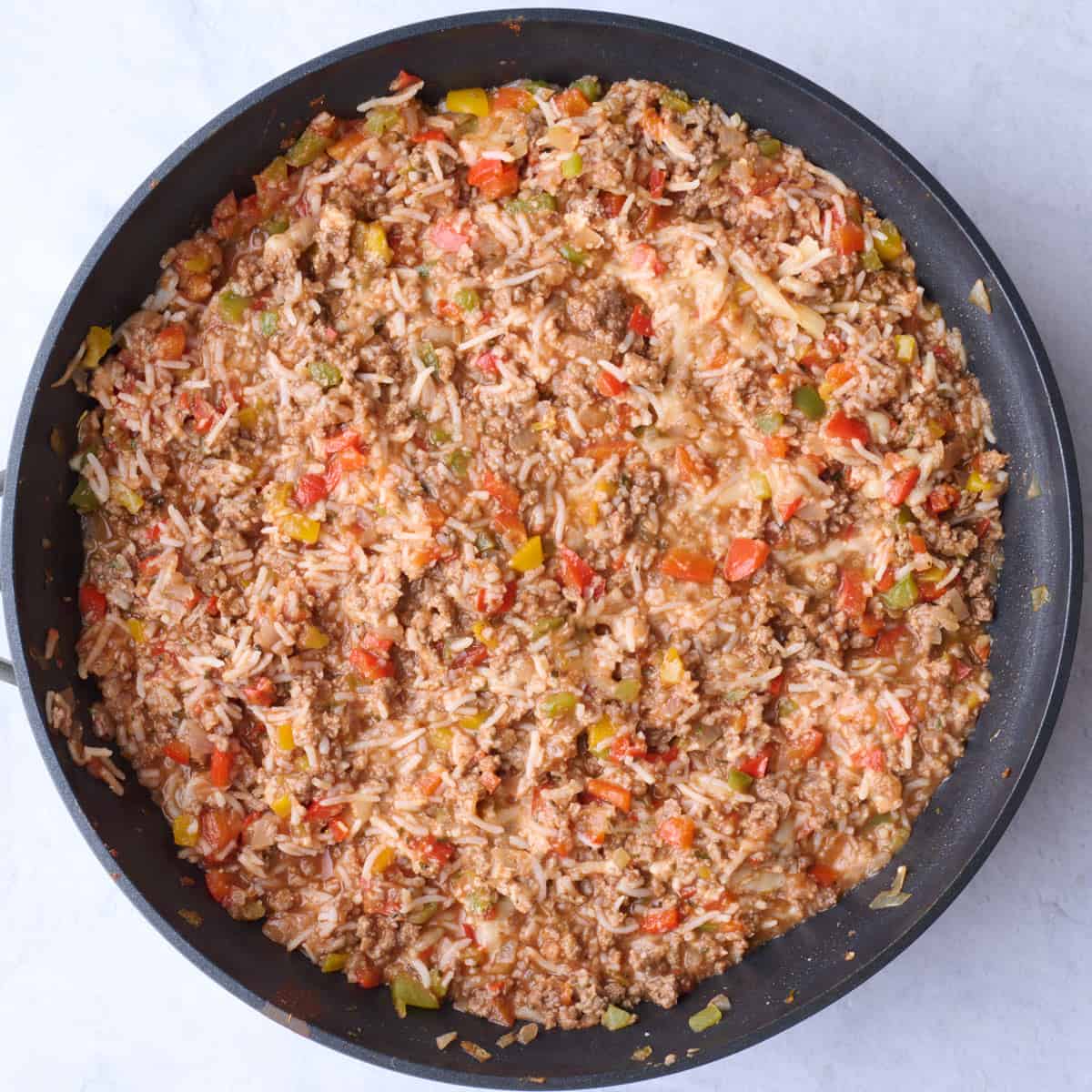Ground beef, rice and tomato stuffed pepper mixture in a skillet after combining.