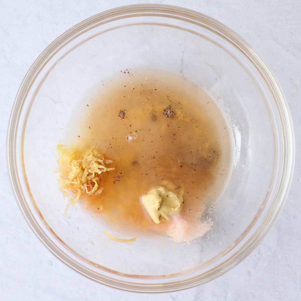 Dressing ingredients for lemon vinaigrette recipe in a small bowl before whisking together.