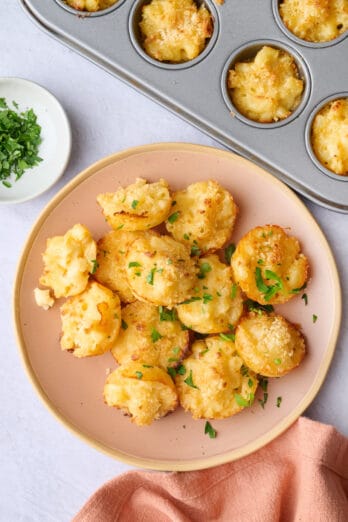 Easy mac and cheese bites with a breadcrumb topping on a small plate with muffin pan nearby.