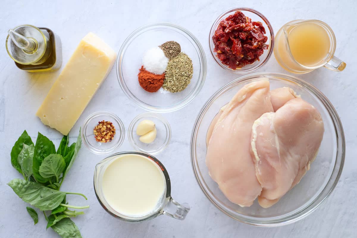 Ingredients for recipe: oil, parmesan, fresh basil, red pepper flakes, garlic, cream, seasonings, sun dried tomatoes, broth, and chicken breasts.