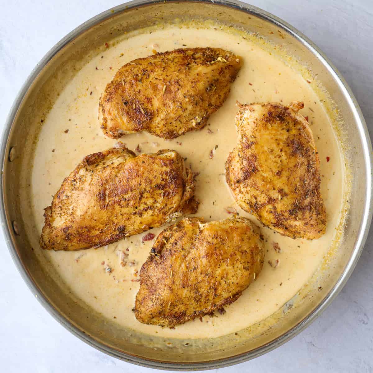 Cooked chicken breasts added back to skillet with marry me sauce.