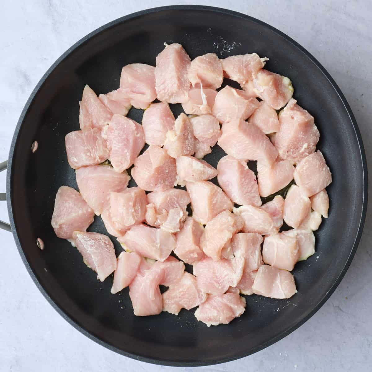 Chicken pieces after tossed with cornstarch added to hot large skillet.