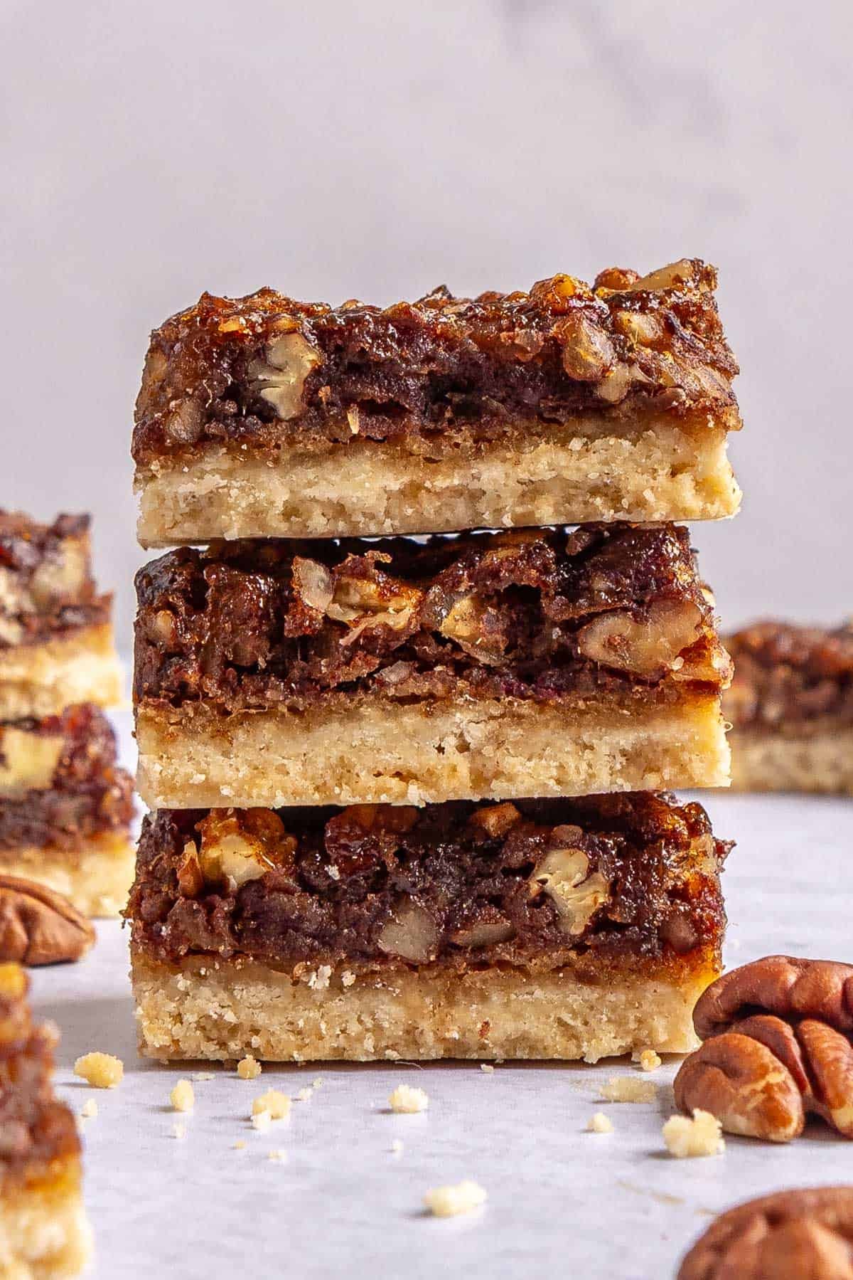 Homemade pecan pie bars made with dates stacked up to show gooey pecan filling and thick crust.