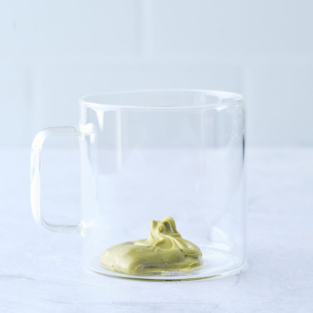 Pistachio cream added to a glass mug.