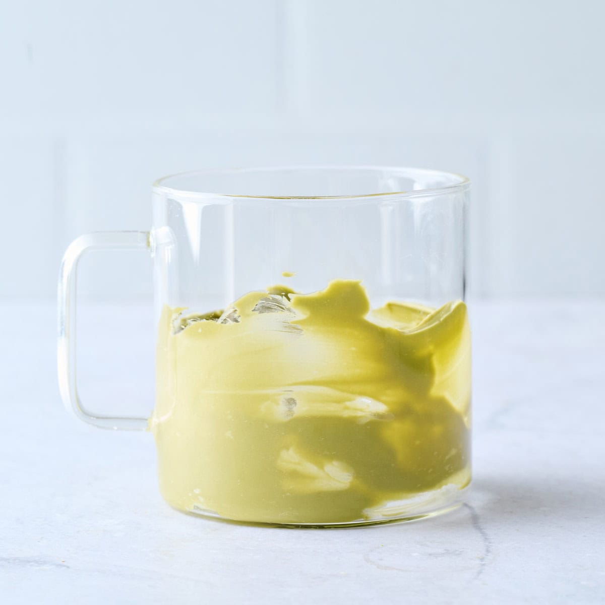 Pistachio cream smeared up the sides of a glass mug for latte recipe.
