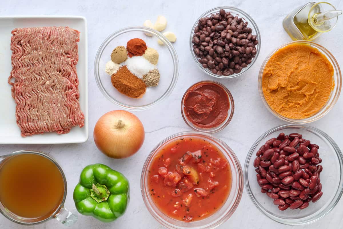 Ingredients for recipe: ground beef, spice blend, garlic cloves, onion, broth, green pepper, fire roasted tomatoes, black beans, tomato pasta, kidney beans, pumpkin puree, and oil.