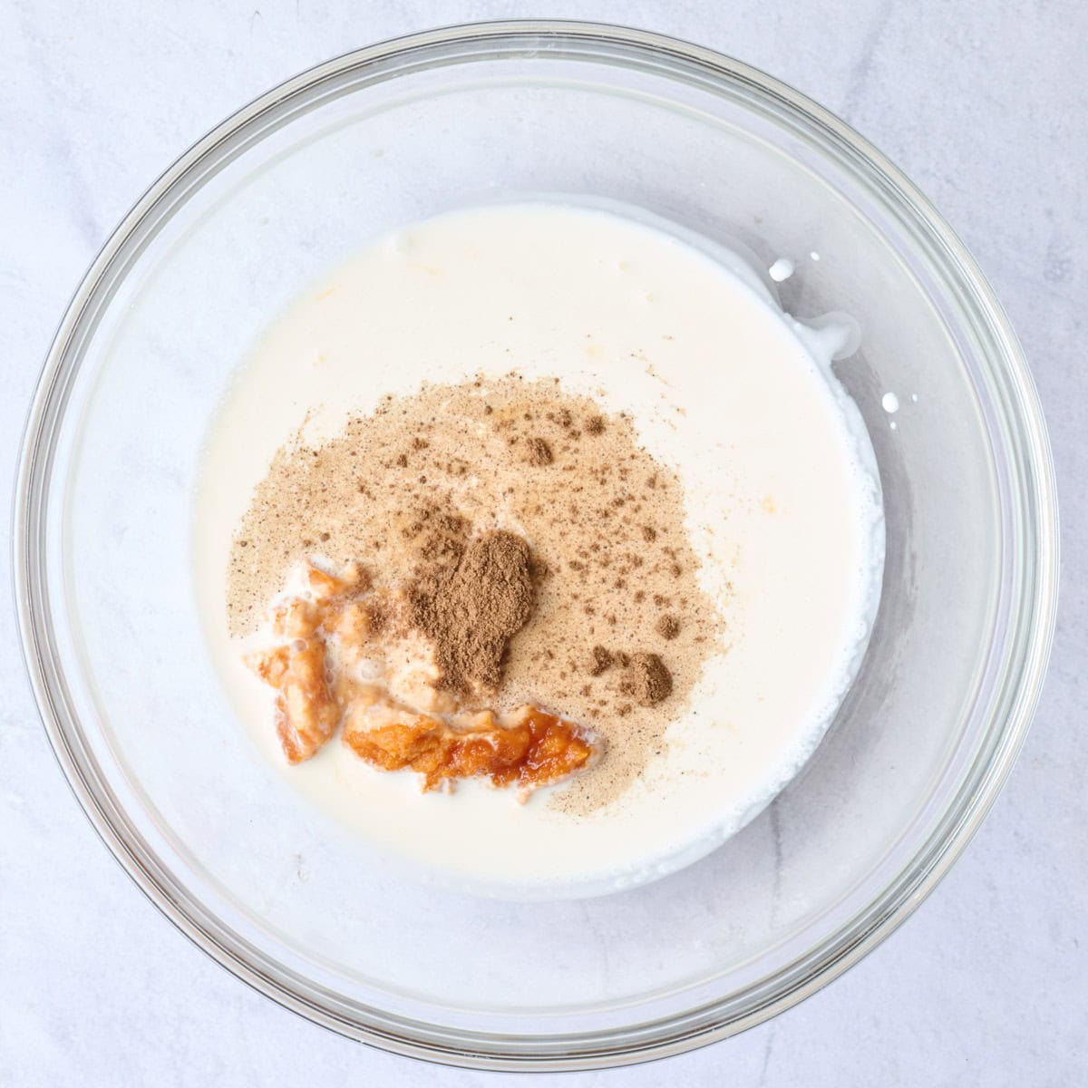 Heavy cream, maple, pumpkin, and spice in a bowl before mixing together for cold brew recipe.