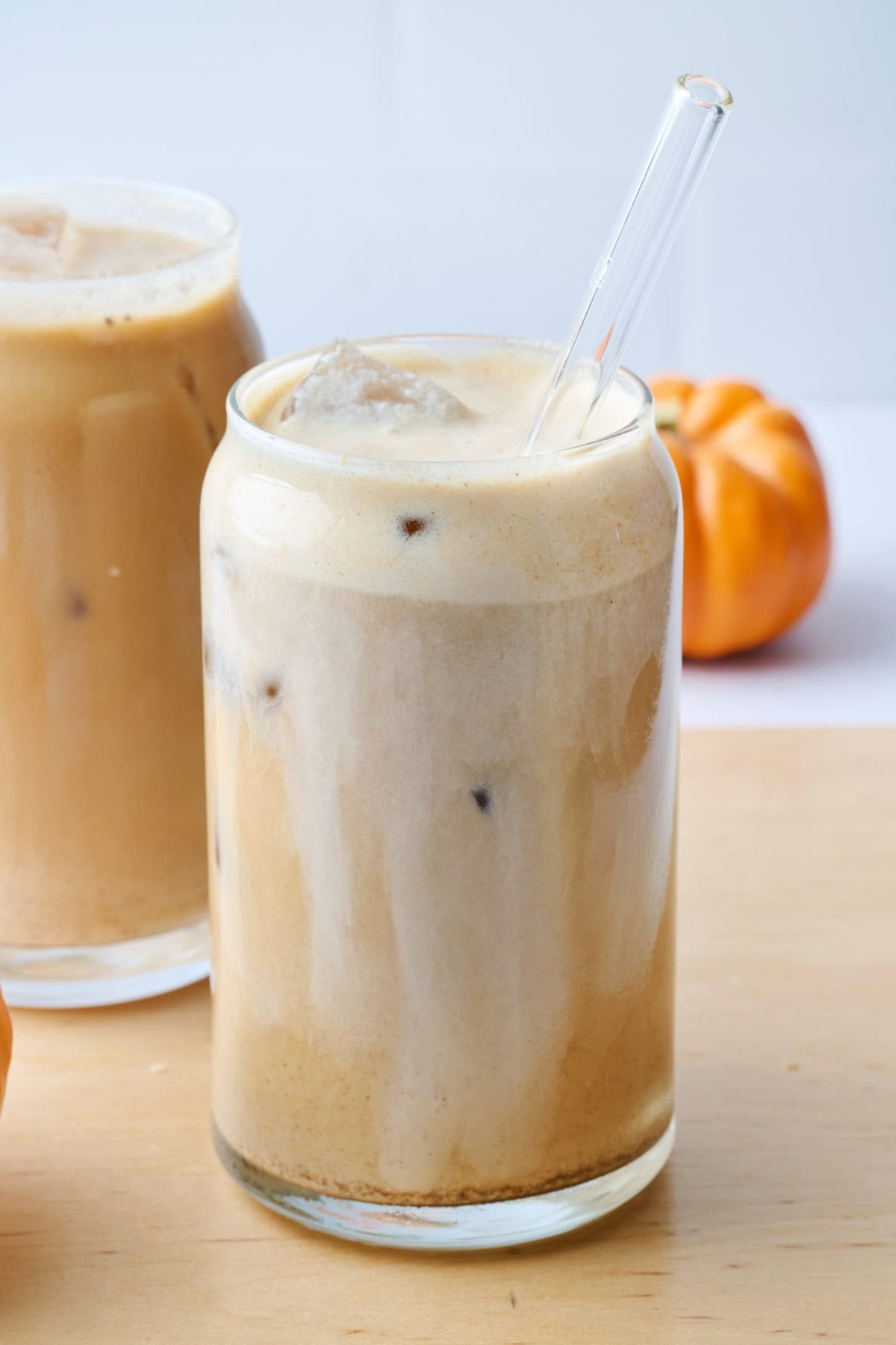 Best pumpkin spice cold brew recipe in a glass with ice and a straw dipped inside.