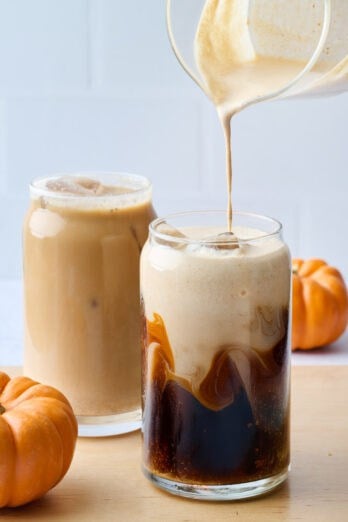 Easy Starbucks copycat pumpkin cream cold brew in two glasses, one prepared and another with pumpkin cream being poured into glass.