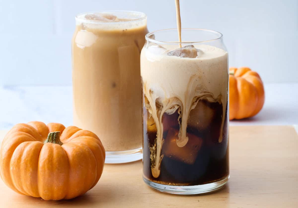 Easy Starbucks copycat pumpkin cream cold brew in two glasses, one prepared and another with pumpkin cream being poured into glass.