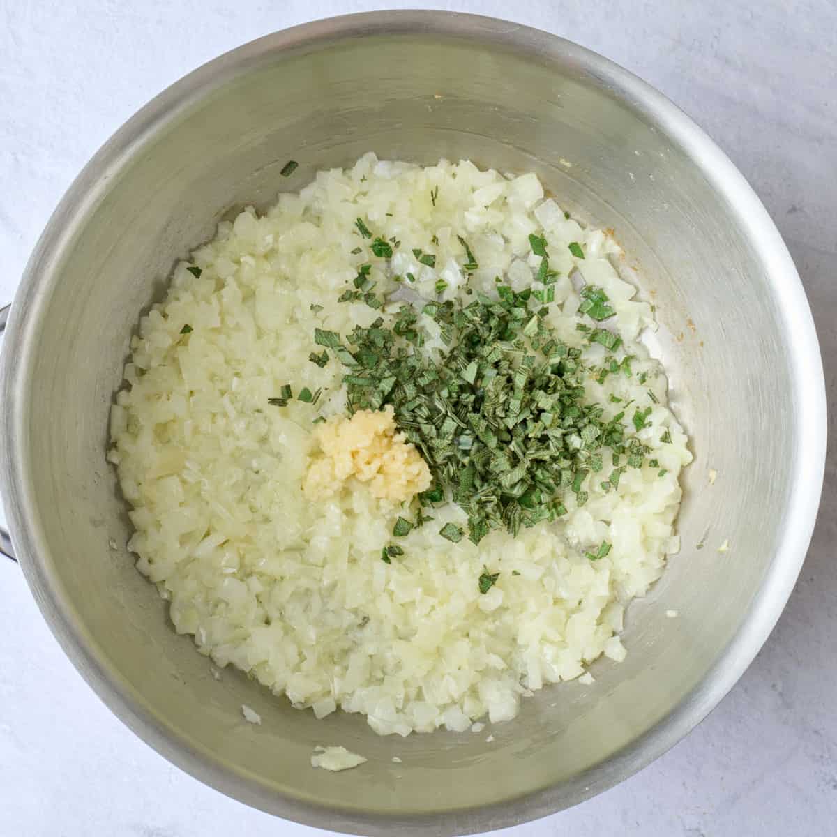 Cooked onions in a pot with garlic and chopped sage added before combining for rice recipe.