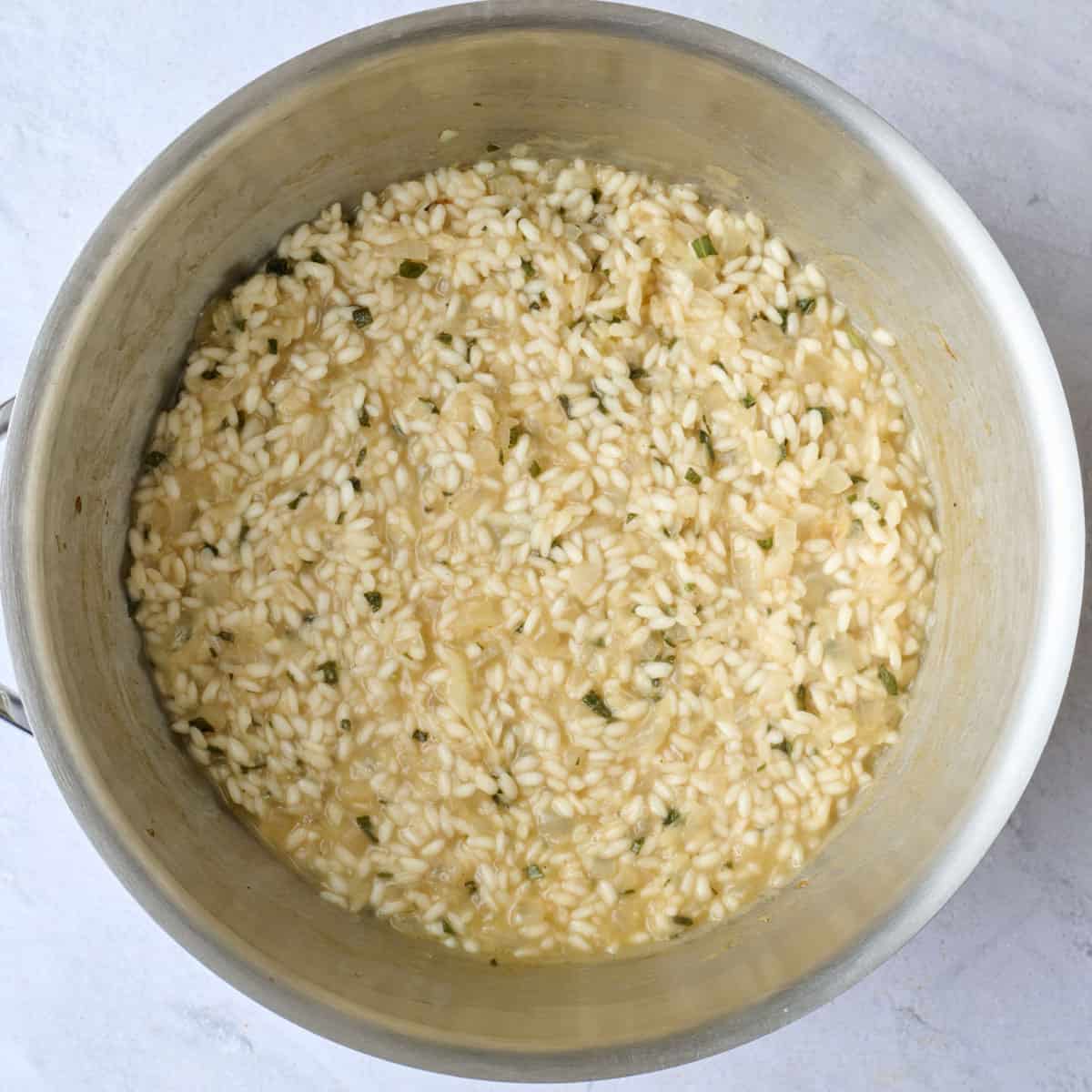 Risotto halfway through cooking to show a thickened sauce.