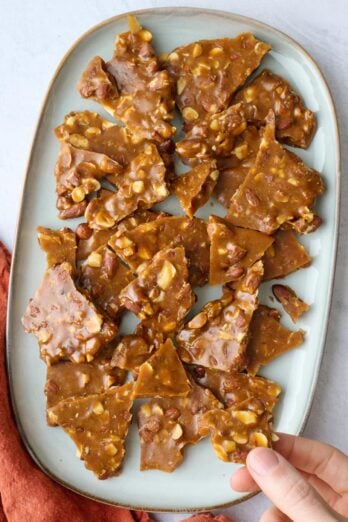 Easy almond brittle pieces on a long platter with pieces of chopped almonds throughout.