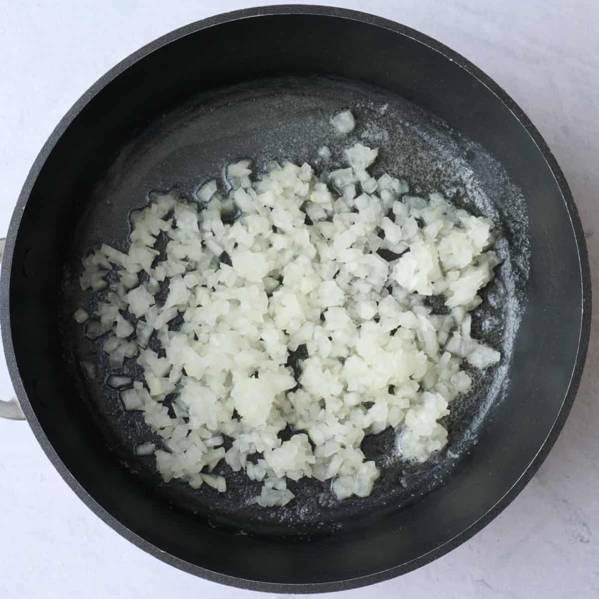 Melted butter in a saucepan with onions added before cooking.