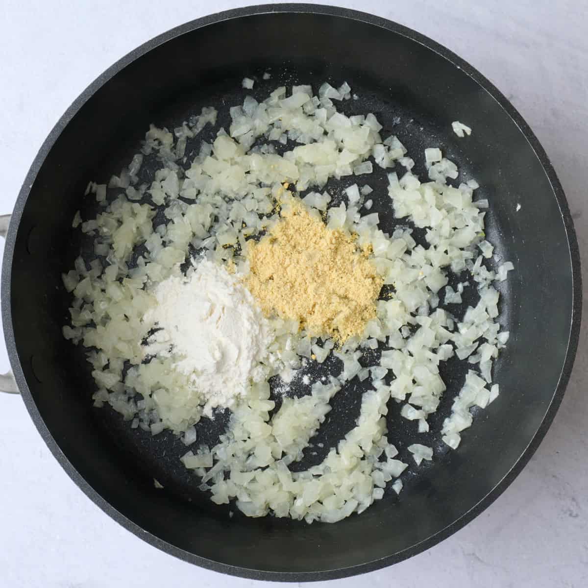 Diced onions after cooking with flour and mustard powder added before stirring.