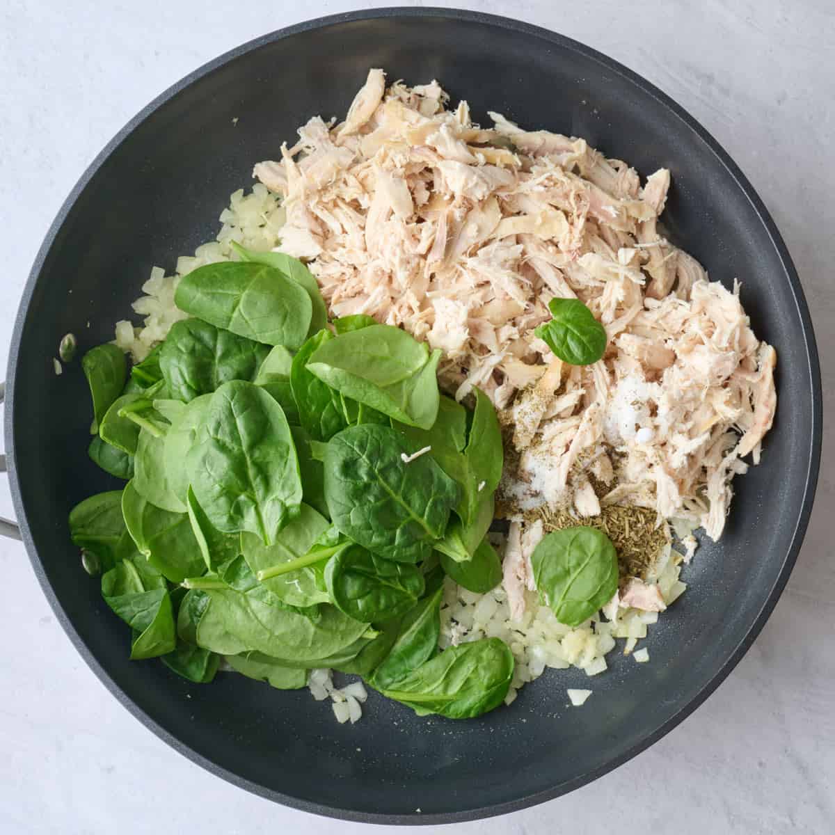 Shredded chicken, spinach and seasonings added to aromatics before mixing for lasagna filling.