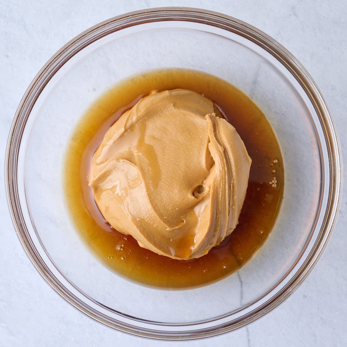Peanut butter and maple syrup in a bowl before mixing.
