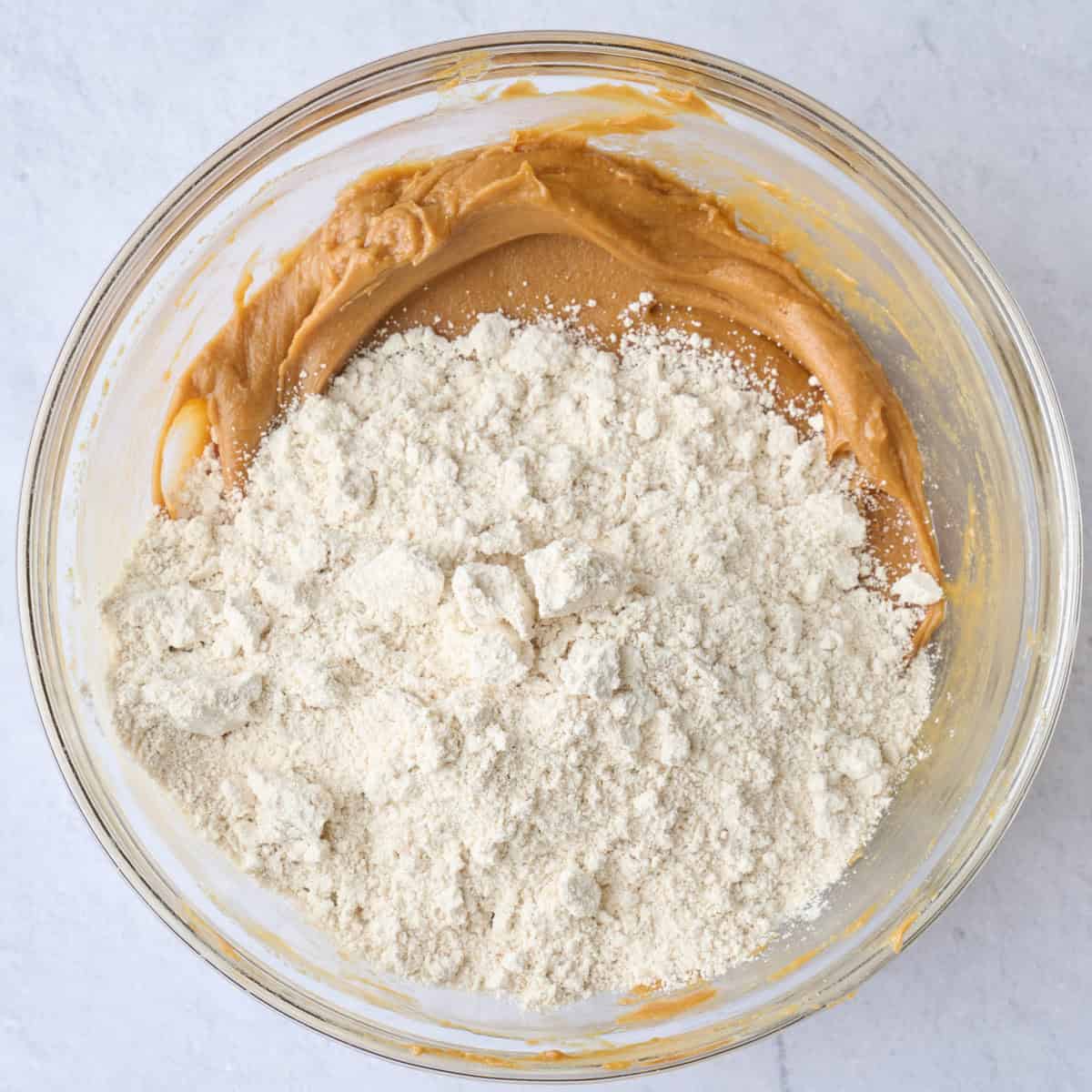 Sweetened peanut butter after mixing with oat flour on top before folding together.