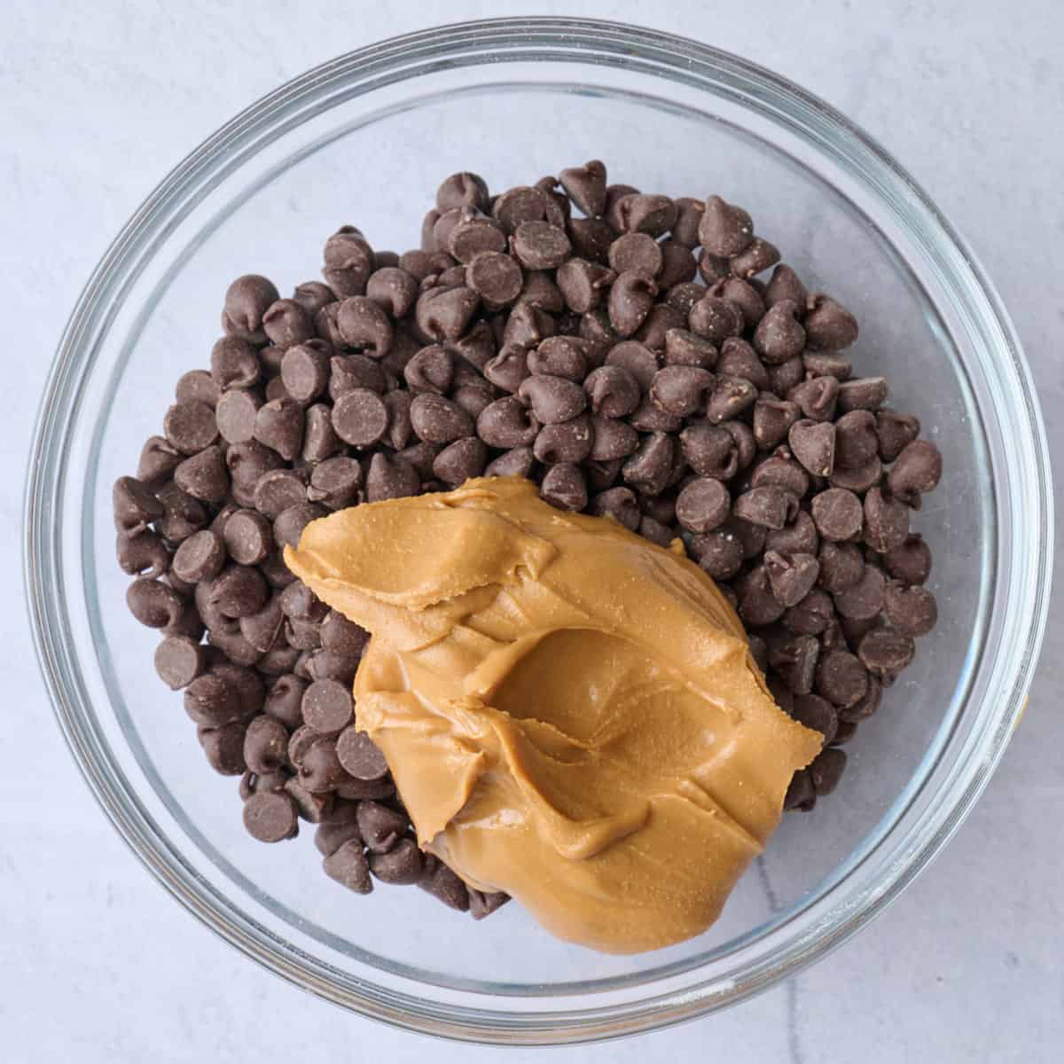 Peanut butter added to a bowl of chocolate chips.