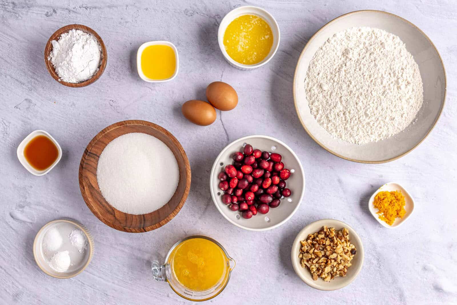 Ingredients for recipe: flour, baking bowder, baking soda, salt, sugar, orange zest and juice, butter, eggs, vanilla, cranberries and walnuts.