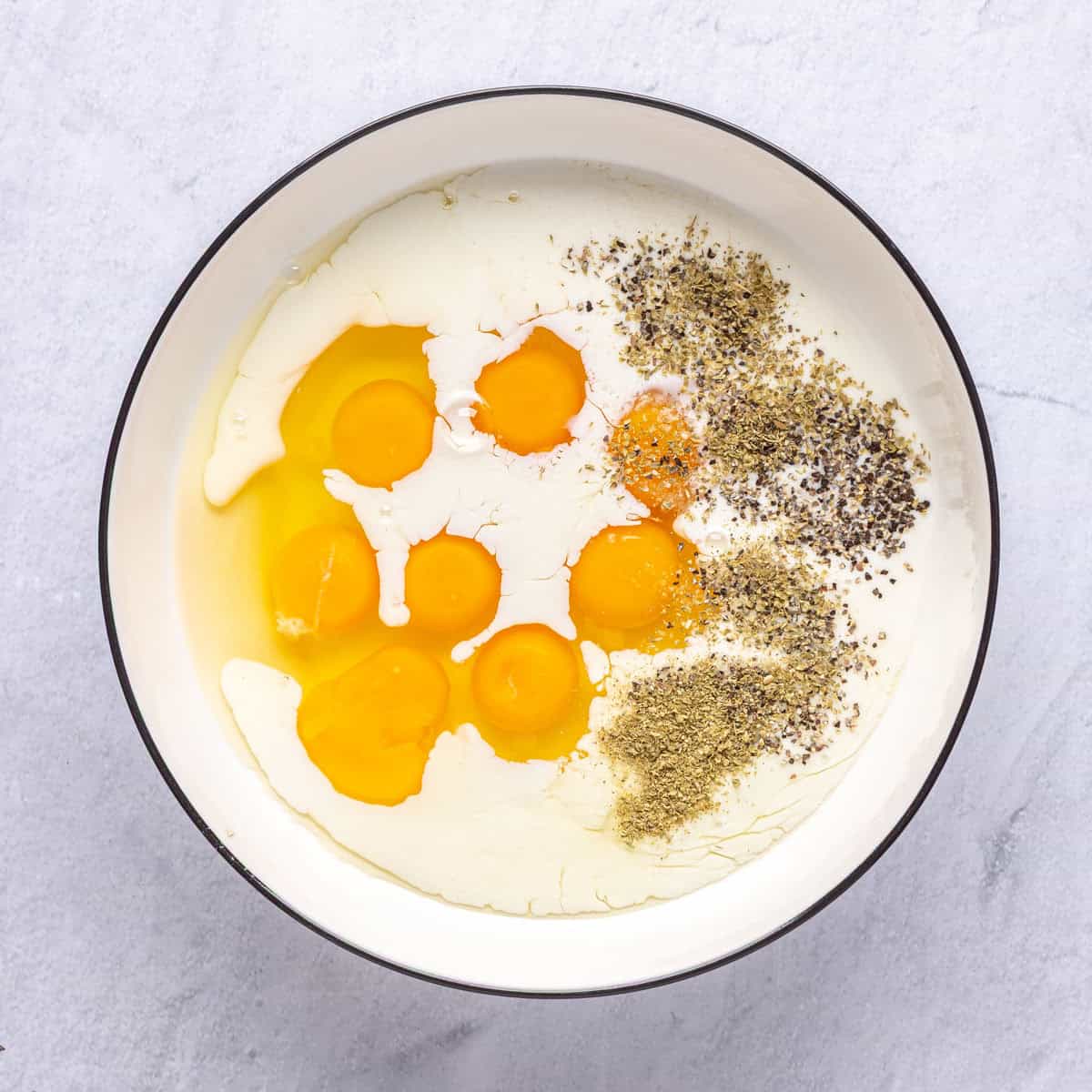 Eggs, milk and seasonings in a bowl before whisking.