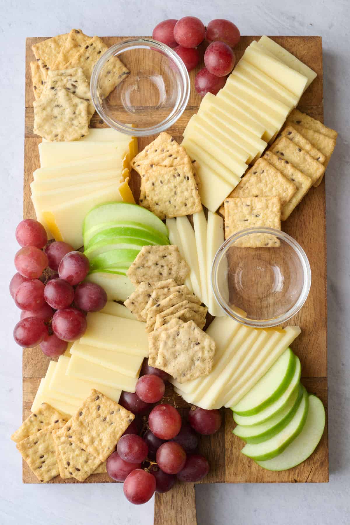 Mixed crackers added to platter with cheese and fruit.