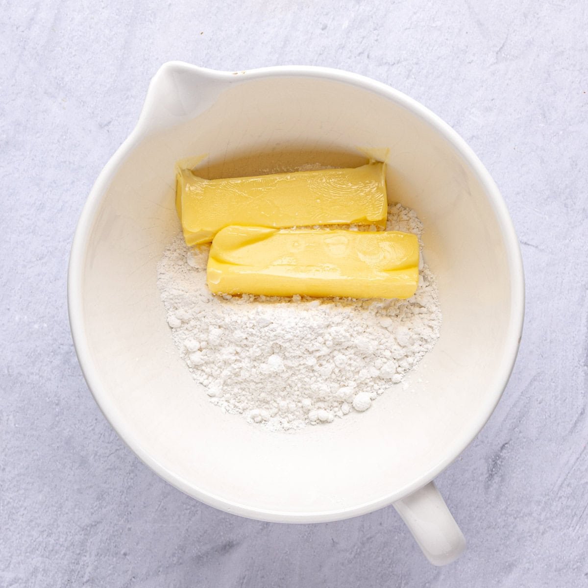 Powdered sugar and softened butter in the bowl of a stand mixer before creaming together.