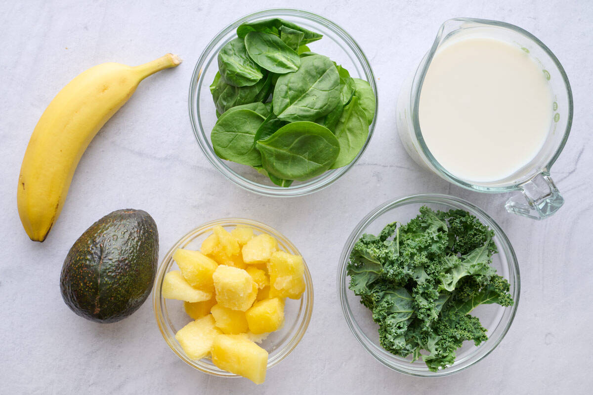 Ingredients for smoothie recipe: spinach, kale, avocado, banana, frozen pineapple and milk.