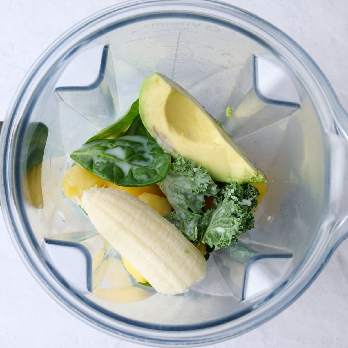 Green smoothie ingredients in a blender before blending.