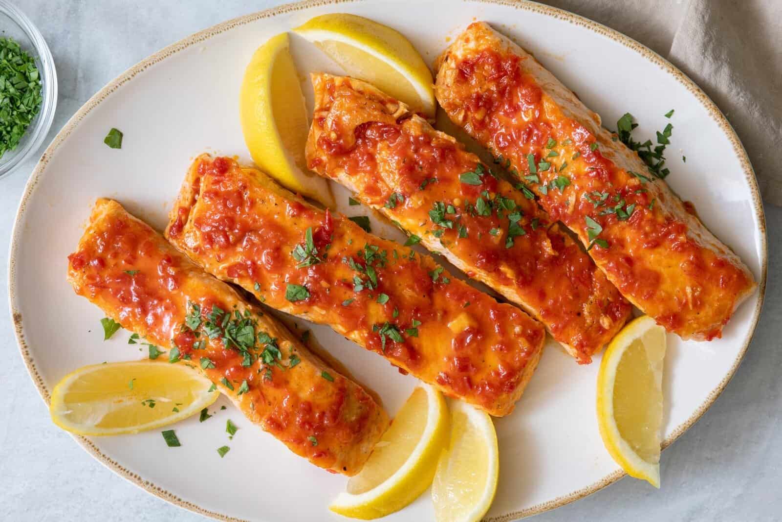 Best sweet and spicy harissa glazed salmon recipe on a platter with lemon wedges.