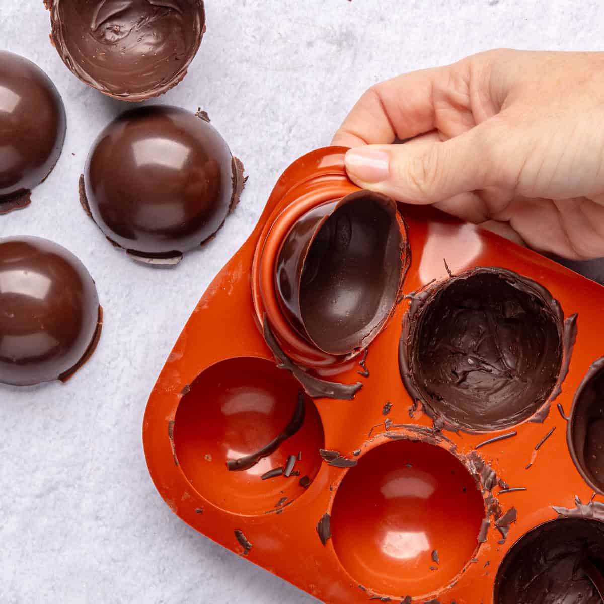 Removing a chocolate shell from mold after hardening with a few already removed.