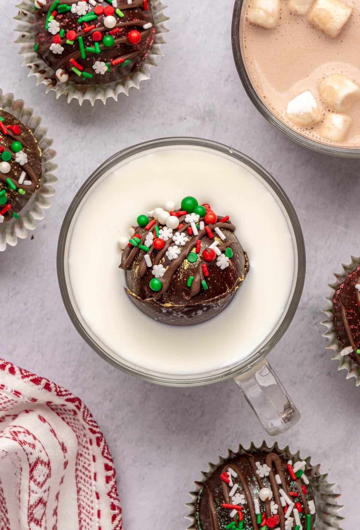 Hot cocoa bomb floating in a warm glass of milk before melting.