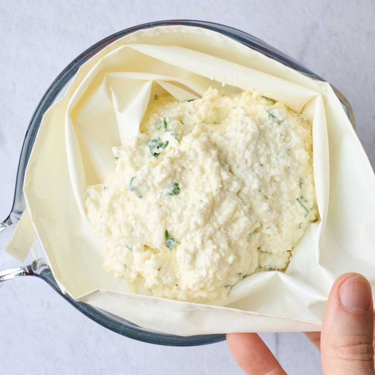 Ricotta mixture for filling manicotti shells added to a piping bag.