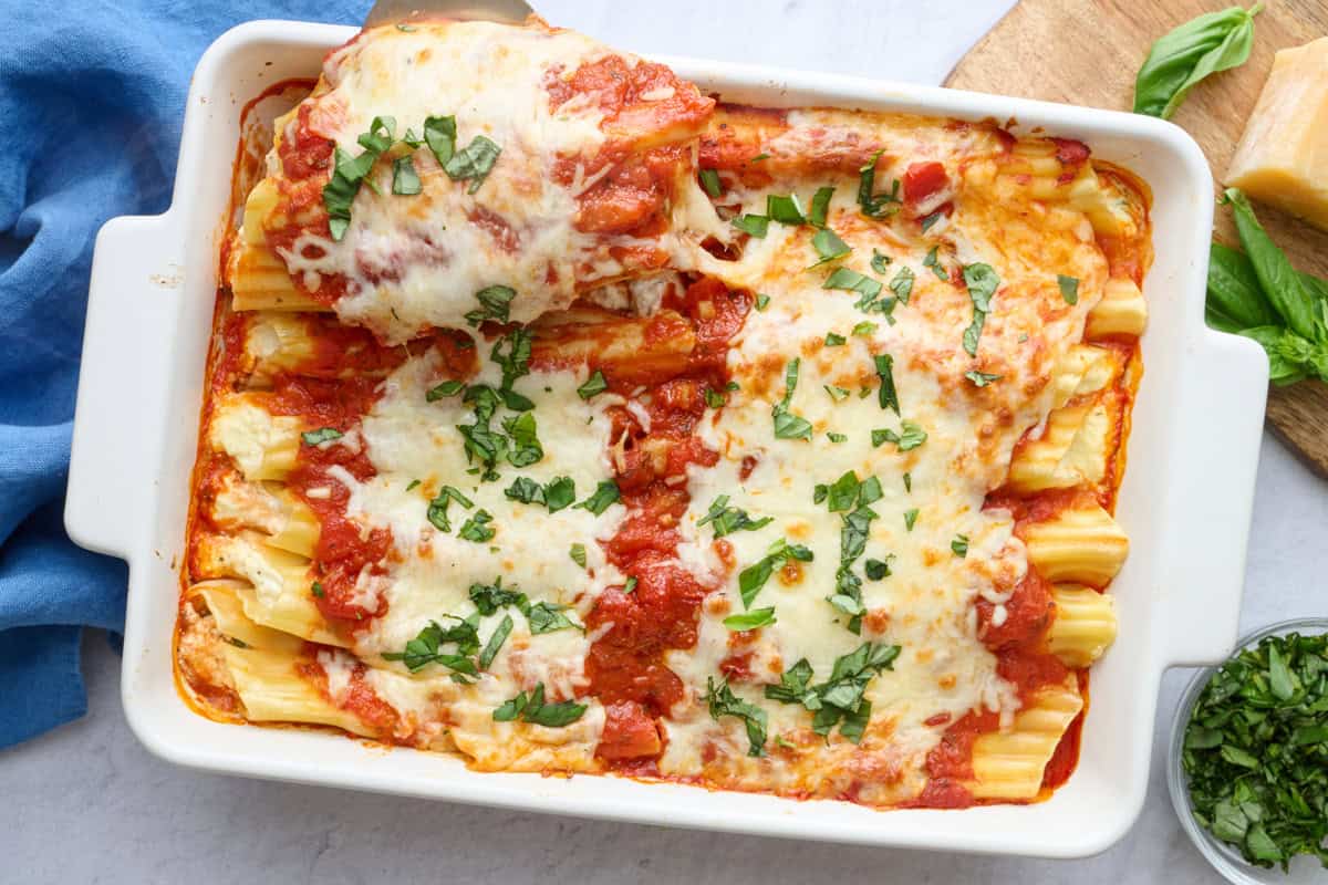 Easy manicotti recipe in a baking dish with a spatula lifting some up.