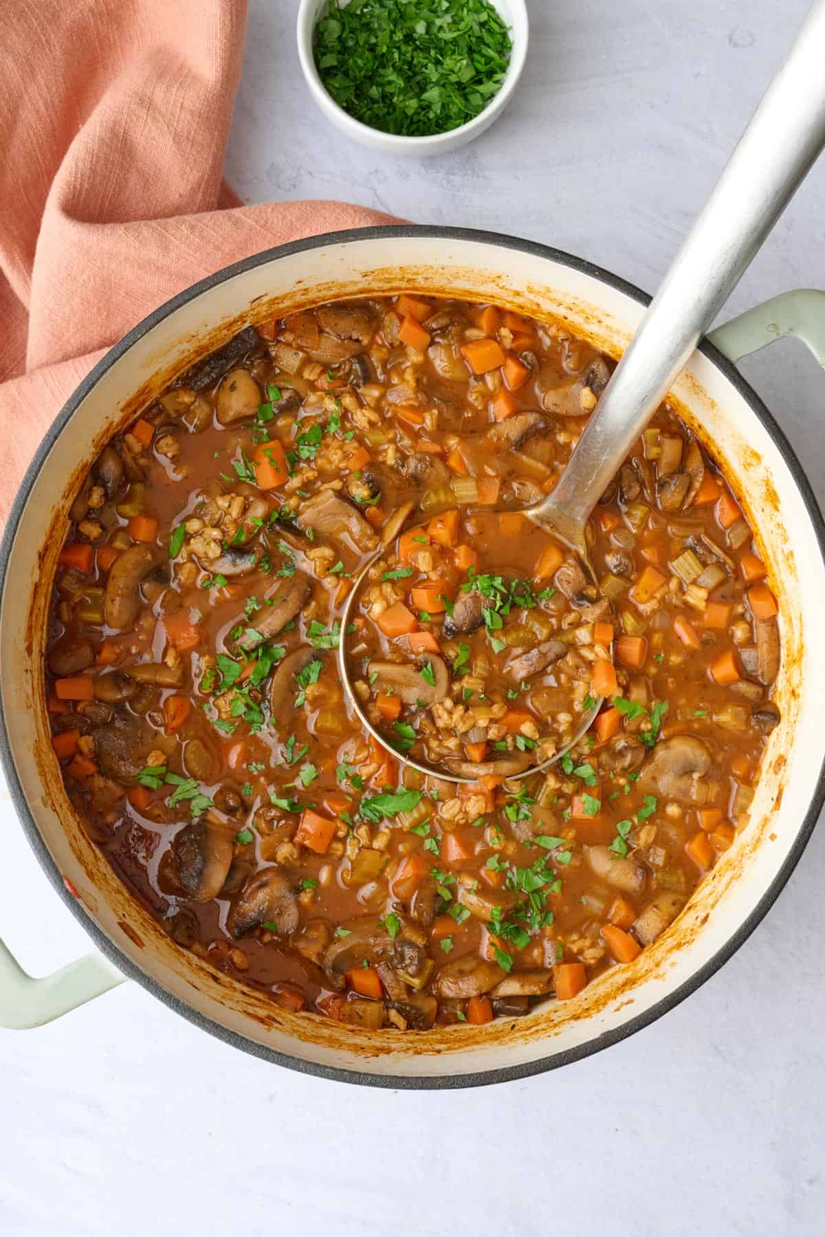 Easy mushroom barley soup recipe in a pot with a ladle lifting some up.