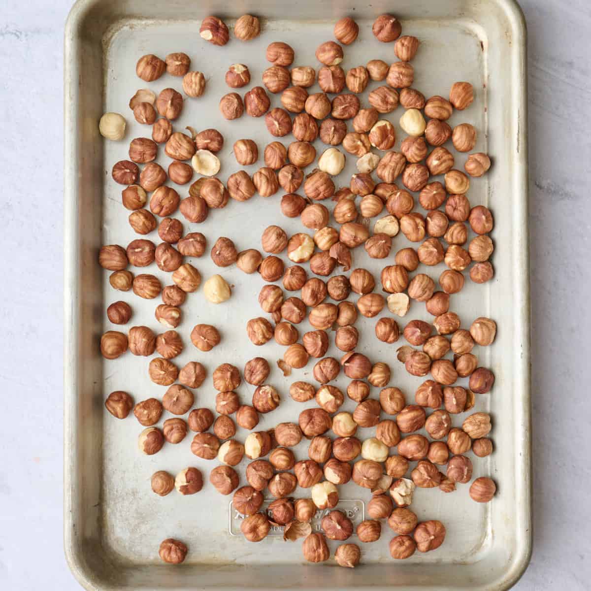Raw hazelnuts on a baking sheet before roasting.